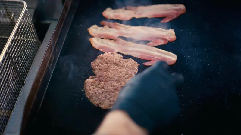 Bacon und Patty auf der Grillplatte im Truck