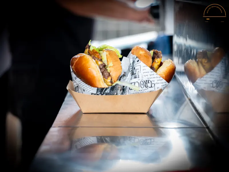 Zwei Burger in einer Papierschale auf der Edelstahl-Theke im Foodtruck