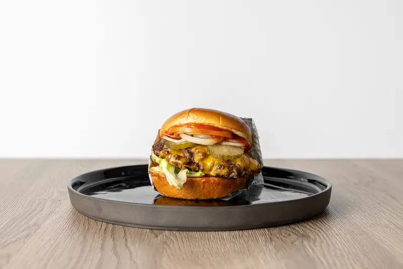 Cheeseburger von Le Bistro Foodtruck mit Cheddar, Pickles, Tomate und Zwiebeln