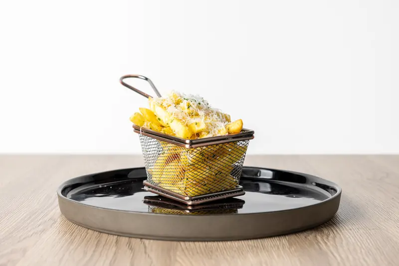 Trüffelpommes mit Trüffelöl und gehobeltem Parmesan im Drahtkorb